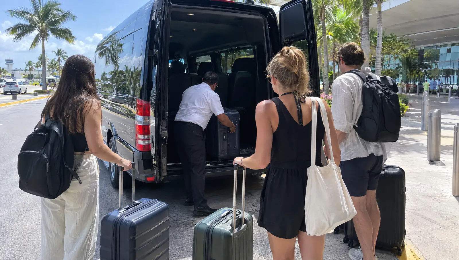 Friends loading suitcases into a private van at the airport
