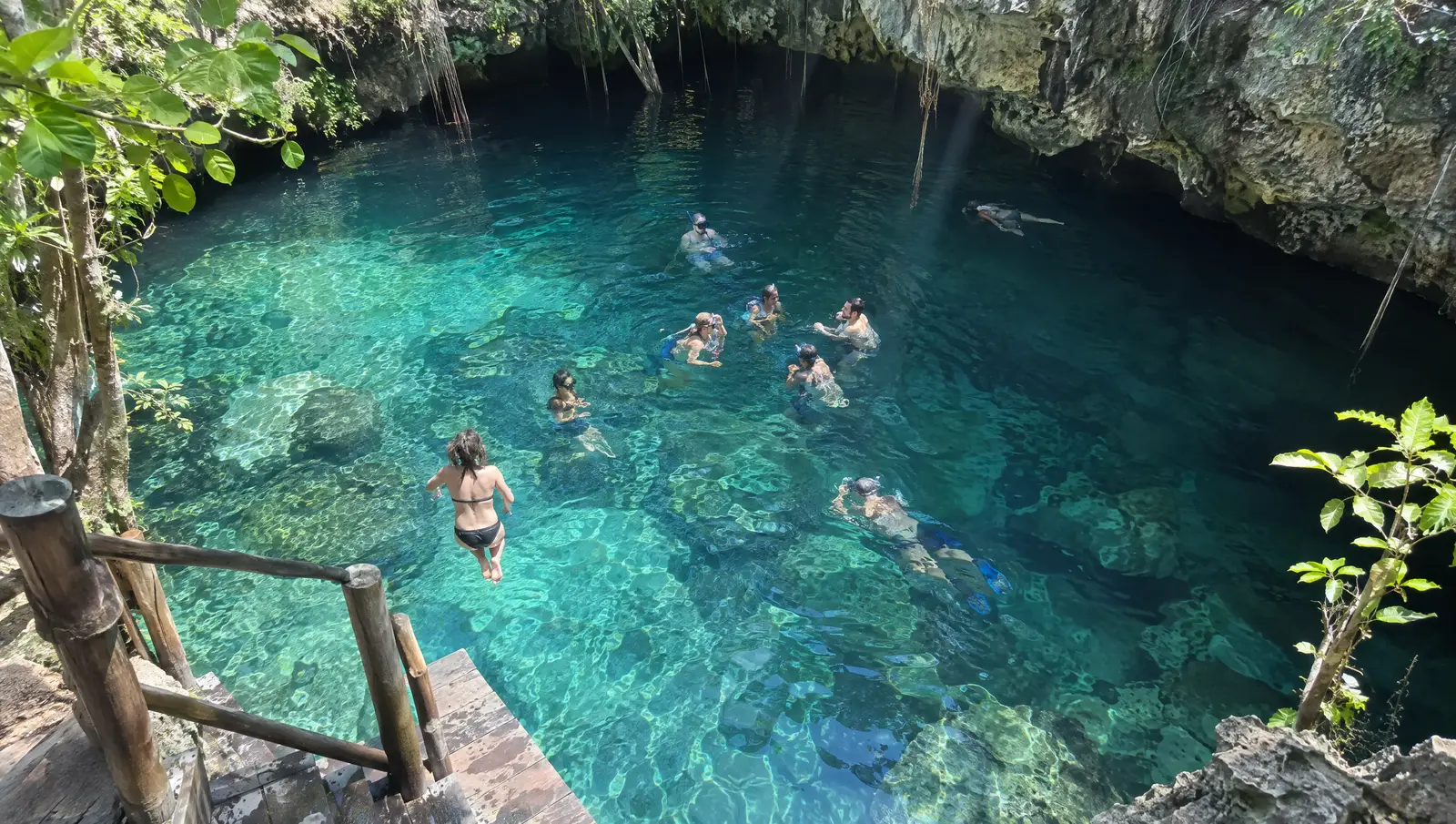 Friends swimming and jumping into a cenote near Tulum